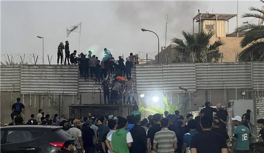 Proteste im Irak nach Koranverbrennung in Schweden: Demonstranten erklimmen eine Mauer an der schwedischen Botschaft in Bagdad. Nach Ankündigung einer weiteren geplanten Koranverbrennung in Schweden haben Demonstranten die Botschaft des Landes im Irak gestürmt und dort Feuer gelegt. Foto: Ali Jabar/AP