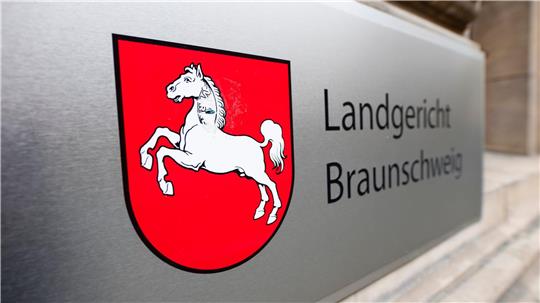 Schild mit rotem Wappen und weißem springendem Pferd neben der Aufschrift 'Landgericht Braunschweig' an einer Steinwand