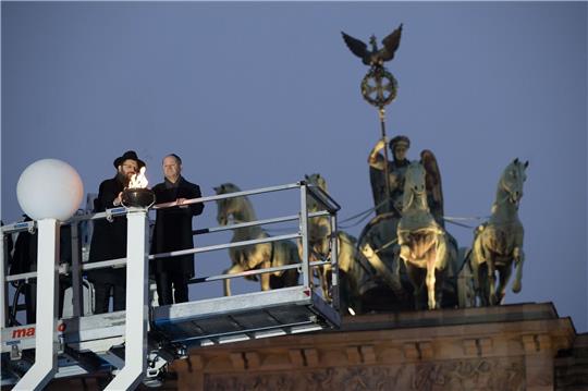 Rabbiner Yehuda Teichtal (l.) und Bundeskanzler Olaf Scholz zünden beim traditionellen zentralen Chanukka-Lichterzünden am Brandenburger Tor in Berlin ein Licht an.
