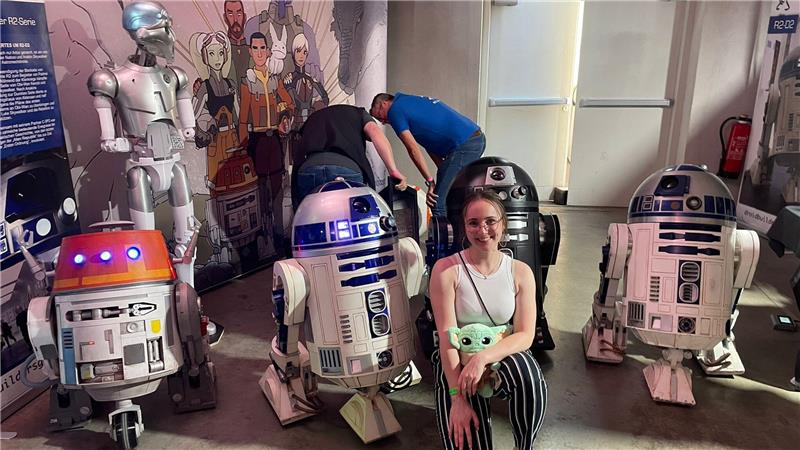 Redakteurin Ronja Heinemann sitzt vor vier Druiden aus der Star-Wars-Reihe