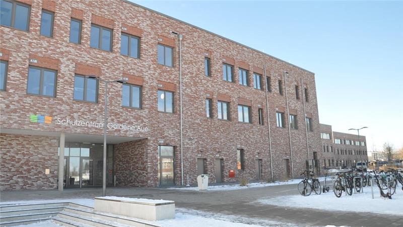 Mehrstöckiges Gebäude mit mehreren Fenstern und einem Eingang mit Glasfront bei winterlichem Wetter mit Schnee auf dem Boden