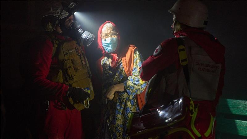 Rettungskräfte evakuieren eine ältere Bewohnerin nach dem Einschlag einer russischen Rakete in ein mehrstöckiges Wohnhaus außerhalb von Kiew.