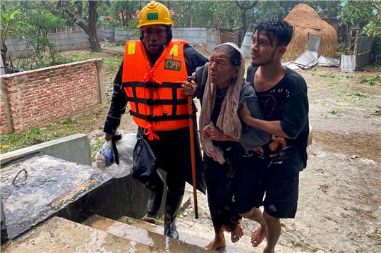 Rettungskräfte helfen einer älteren Frau, eine Notunterkunft in Cox's Bazar zu erreichen.