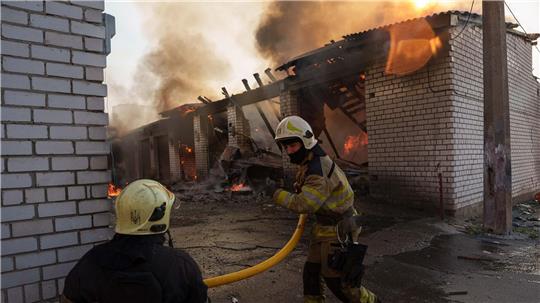 Rettungskräfte löschen ein Feuer in einer Kiewer Autowerkstatt, die durch einen russischen Angriff beschädigt wurde.
