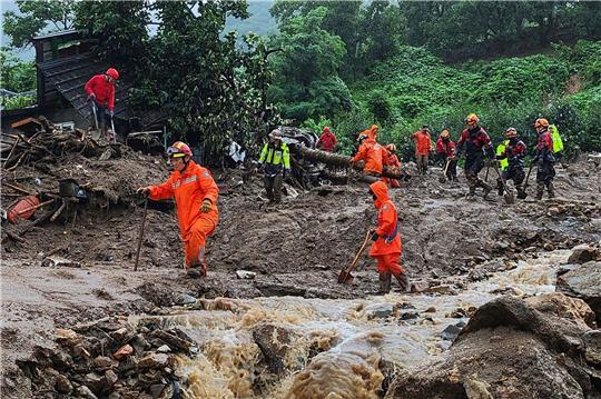 Rettungskräfte suchen  nach Personen in Häusern, die nach durch starken Regen verursachten Erdrutsch eingestürzt sind.