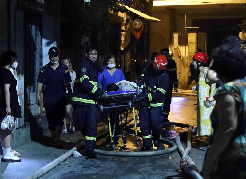 Opferzahl bei Brandkatastrophe in Wohnhaus steigt auf 56 Rettungskräfte tragen eine Person aus einem brennenden Gebäude.