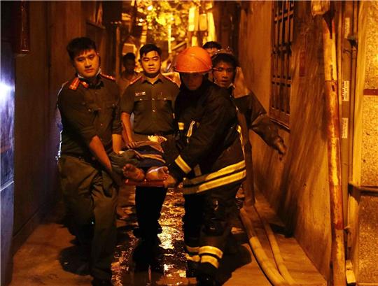 Rettungskräfte tragen eine Person aus einem brennenden Gebäude in der vietnamesischen Hauptstadt Hanoi.