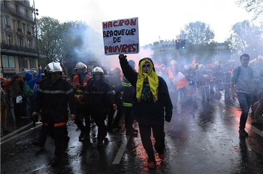 Rettungskräfte und ein Demonstrant mit einem Plakat mit der Aufschrift «Macron, Räuber der Armen» marschieren während einer Demonstration anlässlich des Tages der Arbeit in Paris.