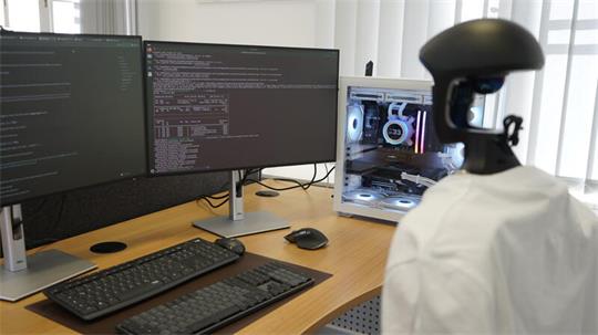 Roboter Bernd der CORE Arbeitsgruppe der TU Clausthal vor einem Coding-Screen. 