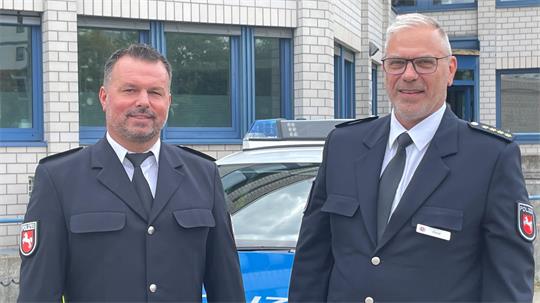 Das Bild zeigt links den neuen Leiter der Polizeiinspektion Goslar, Markus Iwa, und rechts den bisherigen Leiter Rodger Kerst in Uniform vor dem Hauptgebäude der Polizeiinspektion.