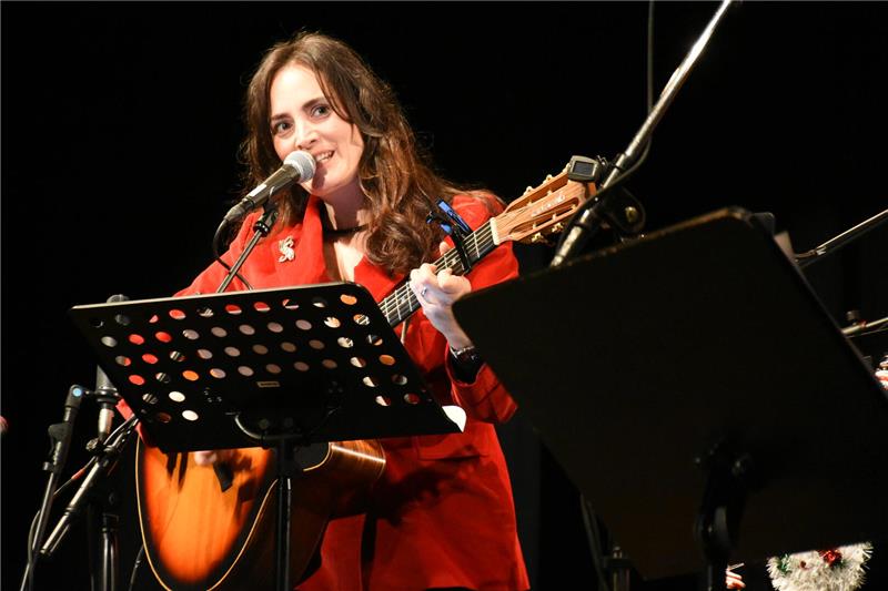 Eine Frau singt und hält eine Gitarre.