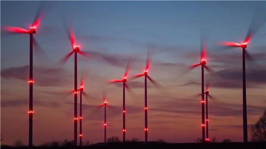 Rote Positionslichter eines Windparks in der Dämmerung.