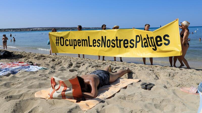 Rund 100 Aktivisten demonstrierten inmitten überraschter Strandurlauber gegen die Auswüchse des Massentourismus.