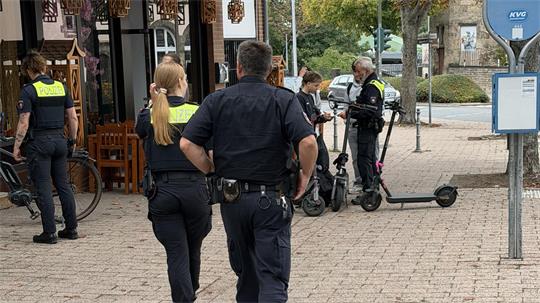 Das Foto zeigt, wie Polizisten mehrere E-Scooter-Fahrer kontrollieren. 