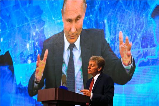 Russlands Präsident Wladimir Putin ist auf einem Bildschirm zu sehen, im Vordergrund steht sein Sprecher Dmitri Peskow (Archivbild). Beide heben das große militärische Potenzial Moskaus hervor.