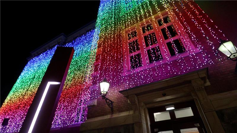 An der Fassade eines Gebäudes hängen LED-Lichterketten, die farbig strahlen.
