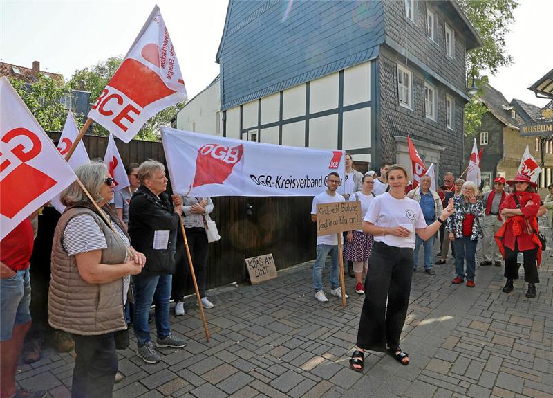 Gruppe von Menschen bei einer Demonstration mit Fahnen und Transparenten vor einem Fachwerkhaus.