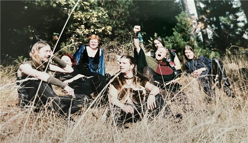 Die Band Moskote sitzt zusammen im hohen Gras.