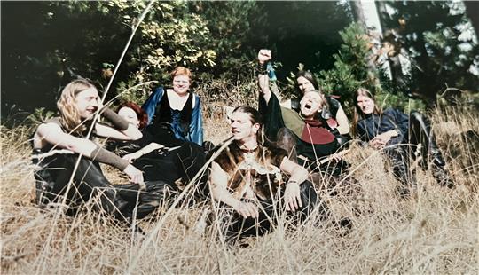 Die Band Moskote sitzt zusammen im hohen Gras.
