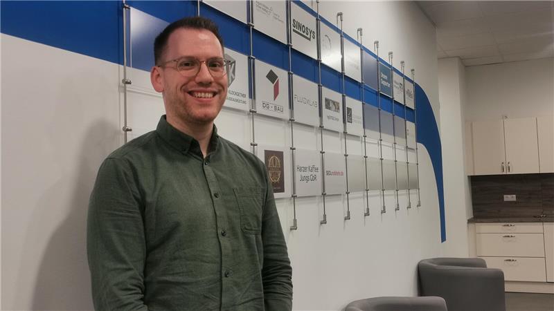 Samet Kibar, Leiter des Gründungszentrums, steht vor einer Wand, auf der Schilder mit den Namen der Mieter angebracht sind.