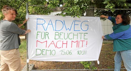Sanna von König (l.) und Maren Vokuhl vom Beuchter Bürgerverein platzieren den Aufruf zur Demo am Marktplatz des Dorfes.