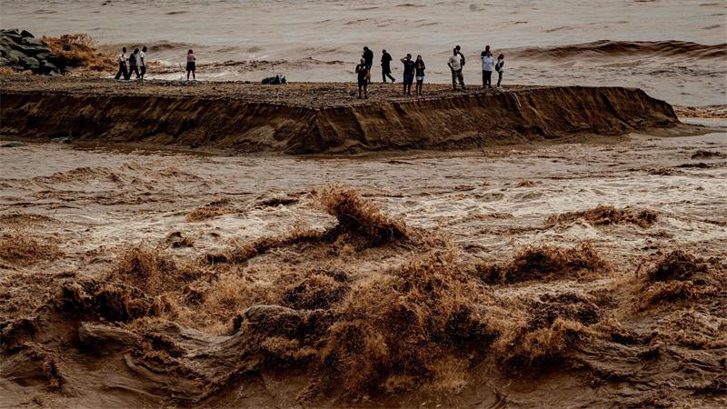 Schaulustige beobachten das aufgewühlte Wasser an der Mündung des Flusses Besòs nördlich von Barcelona.
