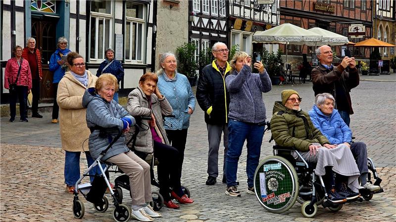 Passanten stehen auf dem Marktplatz und beobachten den Aufbau der Fichte.