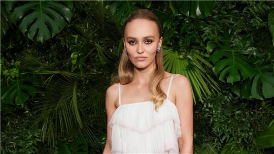 Schauspielerin Lily-Rose Depp schaut in typischer roter Teppich-Pose mit kühler Miene in die Kamera. (Archivbild)