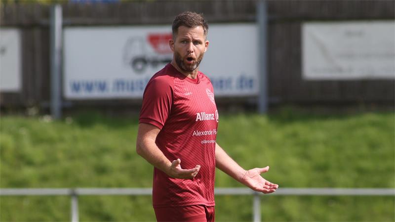 Fußballspieler in rotem Trikot mit der Nummer 21 gestikuliert auf dem Spielfeld