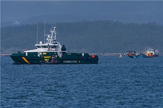 Schiffe der Guardia Civil und des Zolls beteiligen sich an der Bergung eines mutmaßlichen Drogen-U-Boots, von dem nur eine Spitze aus dem Wasser ragt.