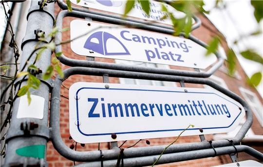 Schilder mit den Aufschriften «Campingplatz» und «Zimmervermittlung» hängen an einer Kreuzung.