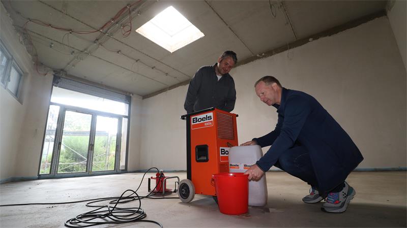 Zwei Männer begutachten in einem Gebäude ein Trocknungsgerät.