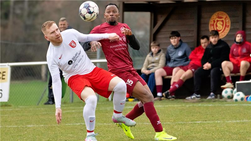 Hahndorf rettet sich in der Schlussminute - Lopez tritt zurück Zwei Fußballspieler in Aktion beim Kopfball, einer in weißem Trikot und roter Hose, der andere in rotem Trikot und roter Hose, im Hintergrund sitzende Personen auf der Bank