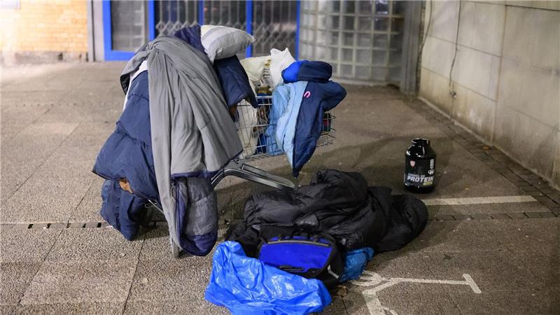 Schlafsäcke, Decken und Kissen liegen in einem Einkaufswagen.
