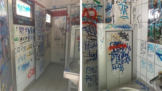 Toilettenkabinen, deren Türen und Wände mit Graffiti und Schriftzügen bedeckt sind.