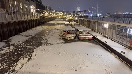 Schnee und Eis ist am späten Abend auf dem Wasser der Elbe in Hamburg zu sehen.
