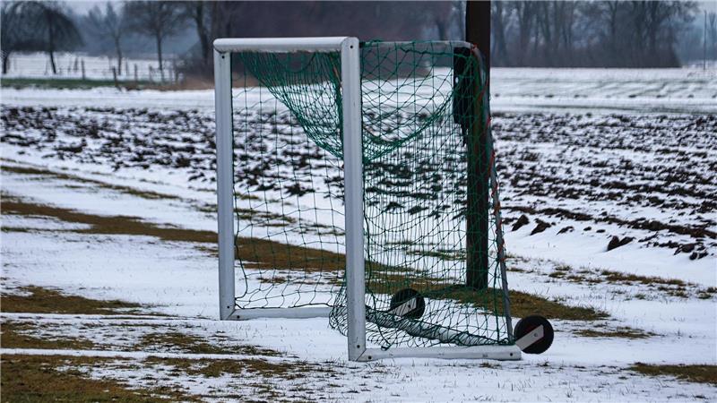 Ein kleines Trainingstor mit grünem Netz auf einem schneebedeckten Feld im Freien