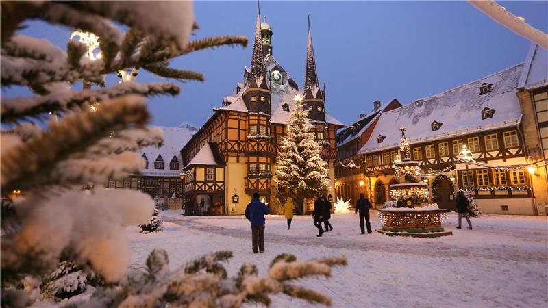 Wo im Landkreis Goslar und der Region Weihnachtsmärkte stattfinden Menschen gehen über den schneebedeckten Marktplatz mit dem Rathaus.