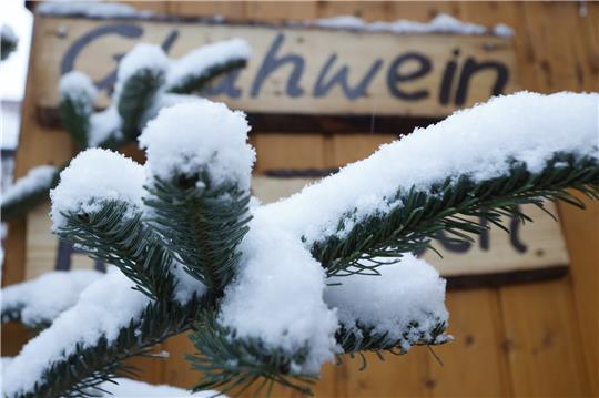 Schneebedeckt sind die Zweige einer Tanne auf dem Weihnachtsmarkt im Stadtgebiet von Wernigerode. Foto: Matthias Bein/dpa