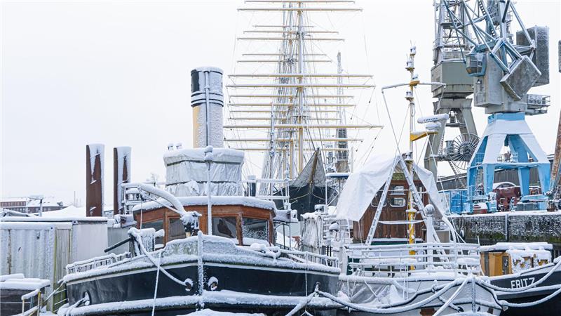 Schneebedeckte Schiffe liegen im Museumshafen in Hamburg.