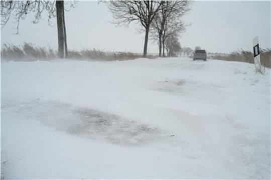 Schnee und eine von Schnee verwehte Straße.