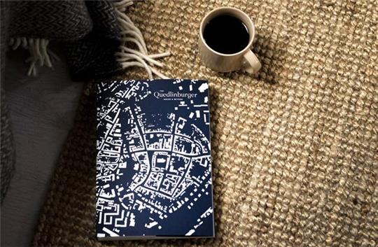 Der Umschlag des Buchs "The Quedlinburger" und eine Tasse Kaffee.