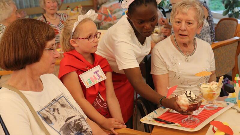 Italienisches Eiscafé für Senioren im Goslarer Haus Abendfrieden Schülerin Theresa und die angehende Heilerziehungspflegerin Broniar Nalunga servieren das Eis am Tisch von Claudia Hagedorn (links) und Christa Wolf.