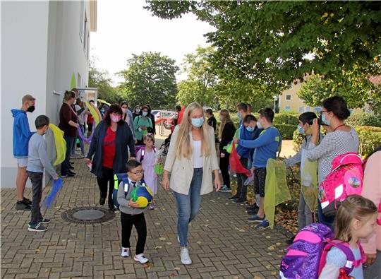 Schülerinnen und Schüler stehen Spalier für die Abc-Schützen der Schule am Harly (rechts). Pfarrerin Sandra Jang hat zum großen Tag Puppe Frida mitgebracht (Foto unten). Fotos: Hohaus