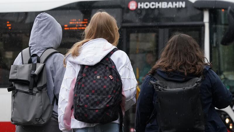 Schülerinnen und Schüler steigen in einen Bus.