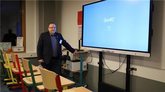 Schulleiter Klaus Scheller zeigt einen Klassenraum mit Smartboard und neuer Einrichtung.