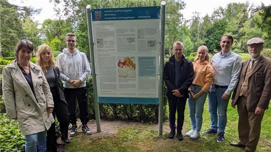 Schulleiterin Inga Rau (l.) und die Schüler Greta Lohde, Pay Philipp Symicek, Mirko Gallun sowie Emilia Zimmermann präsentieren ihre Infotafel mit dem Geschichtslehrer Lukas Friedrich und Rainer Bendick vom Volksbund.