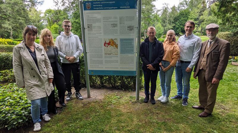 Schulleiterin Inga Rau (l.) und die Schüler Greta Lohde, Pay Philipp Symicek, Mirko Gallun sowie Emilia Zimmermann präsentieren ihre Infotafel mit dem Geschichtslehrer Lukas Friedrich und Rainer Bendick vom Volksbund.