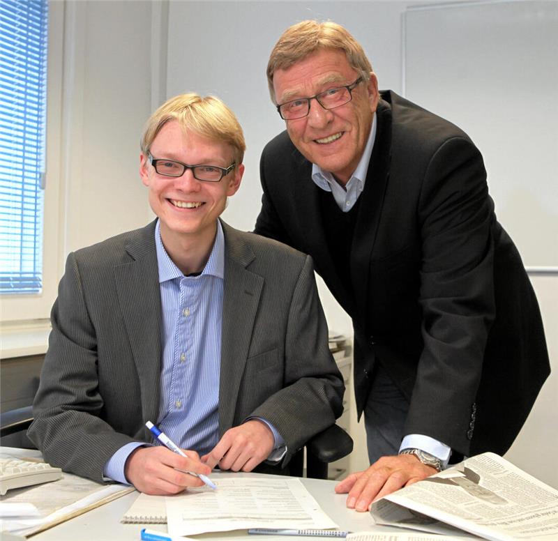 Herr des Goslarer Geldes: Dr. Pascal Bothe (CDU) mag Zahlenarbeit Zwei Männer in Anzügen sitzen an einem Tisch mit Dokumenten, einer schreibt mit einem Stift, der andere lehnt sich mit einer Hand auf den Tisch.