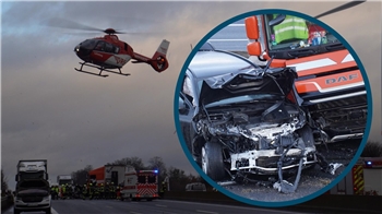 Ein Helikopterfliegt über mehrere Fahrzeuge, die auf einer Straße stehen.